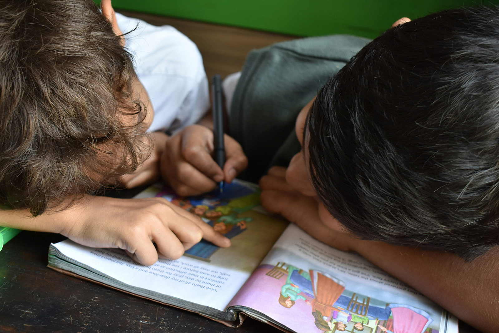 two boys leaning over a book