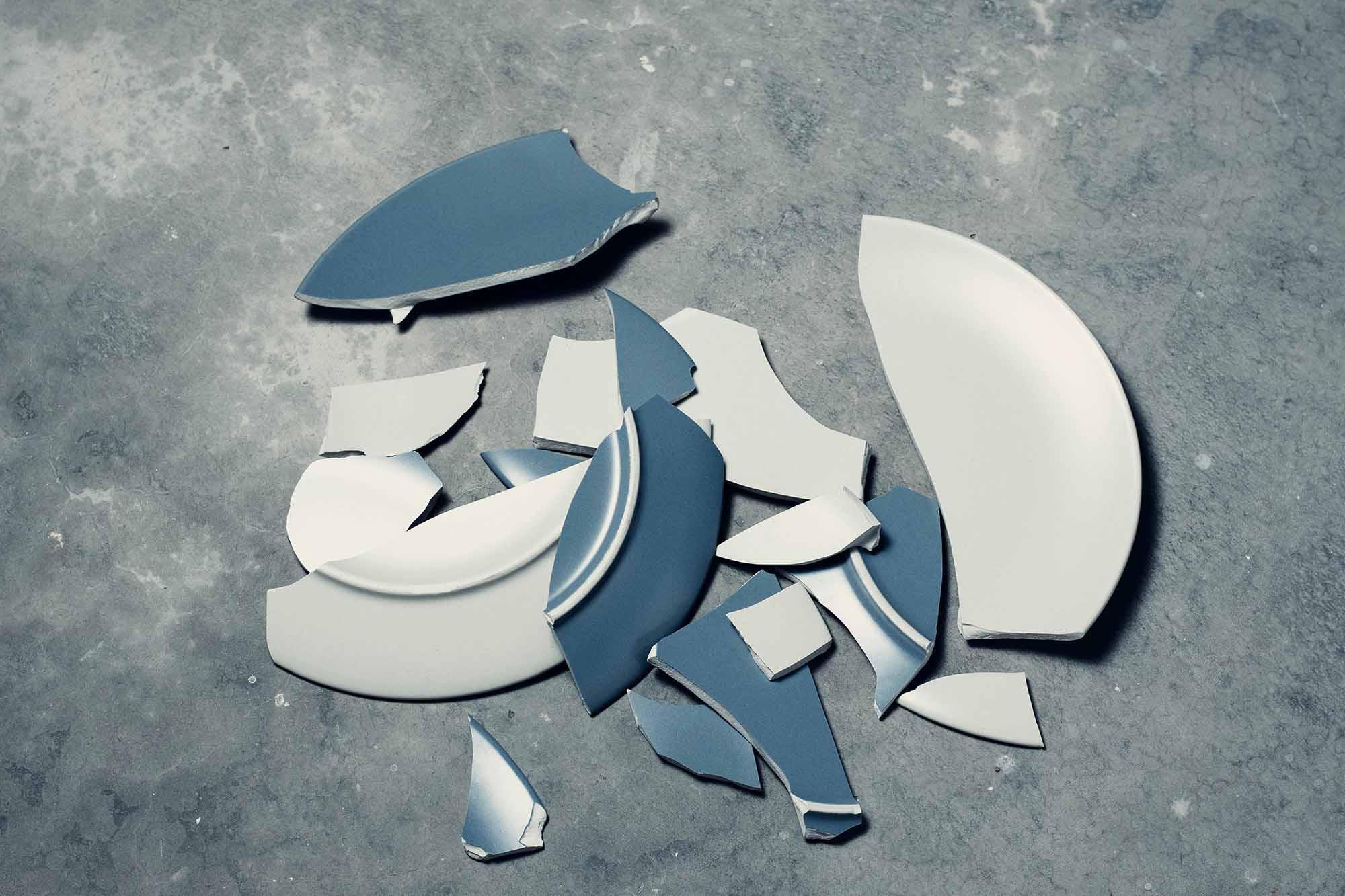 broken blue and white plates on a grey surface